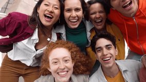 Multicultural group of young people laughing at camera together - Happy friends having fun hanging outside on summer day - Real people life style concept