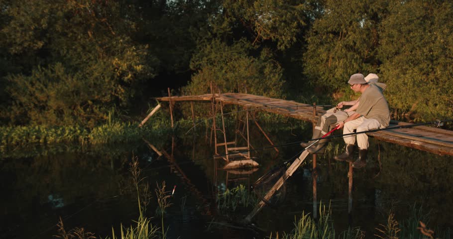 Two men fishing and drinking beer on wooden dock