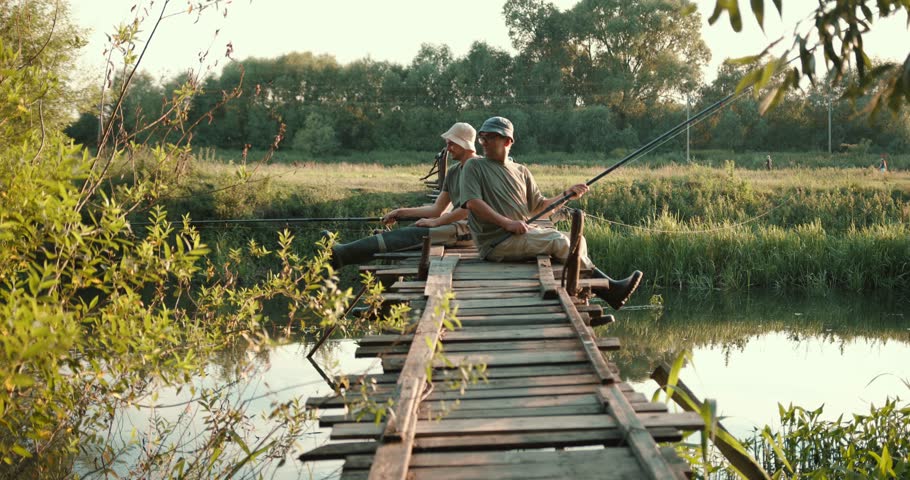 Two men fishing and drinking beer on wooden dock