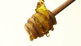 Sweet Honey Cascade: Delightful Flow of Honey from a Wooden Spoon on White Background