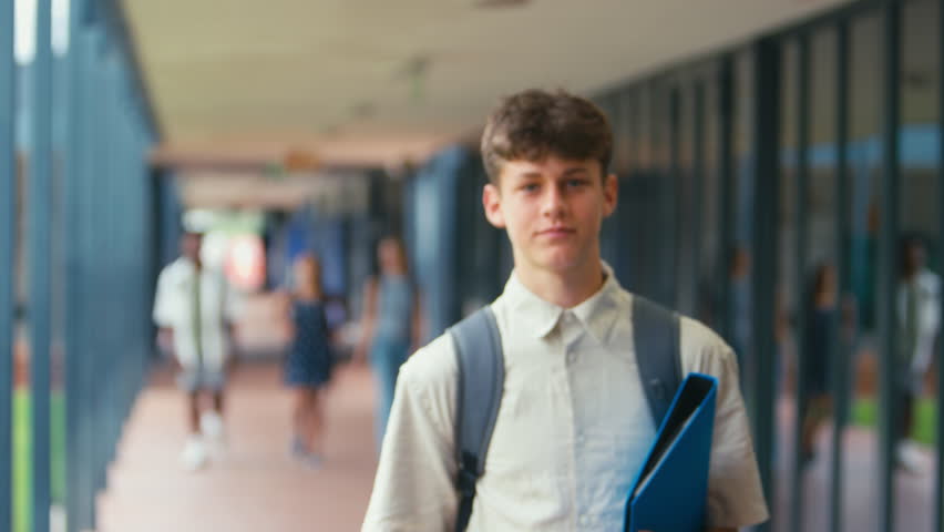 Portrait of male high school student walking outside classrooms with backpack and files - shot in slow motion Royalty-Free Stock Footage #1103863187
