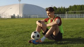 Portrait of young man football player sitting on soccer field and using smartphone - Powered by Shutterstock - Get 15% off with code: PIKWIZARD15