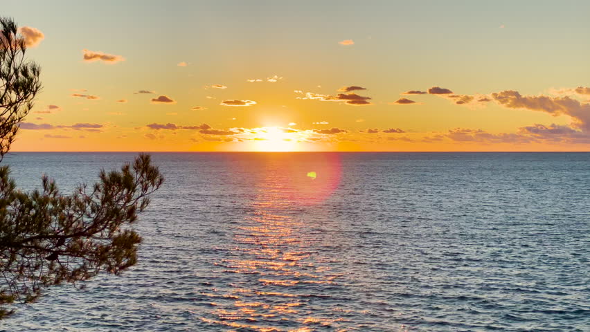 LENS FLARE Golden summer sun setting behind horizon of blue wavy Adriatic Sea. Wonderful moment at end of the day on holiday destination of island of Hvar. Stunning seascape in golden colors of sunset