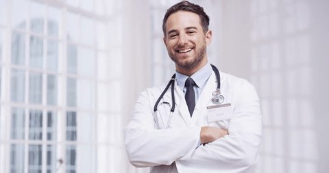 Healthcare, happy and a man doctor arms crossed in the hospital for insurance or medical treatment. Portrait, medical and smile with a young male medicine professional standing in a health clinic Video de stock