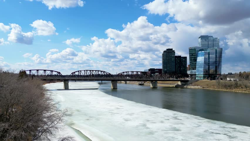 Aerial view of a bridge going over Saskatchewan River during a vibrant sunrise in the Spring Season. Taken in Saskatoon, SK, Canada. 