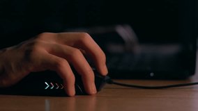 Close up of man gamer hands using computer mouse is playing video game at night. Male hacker breaks into system, coding or data analysis programmer, developer or employee on tech for software code.