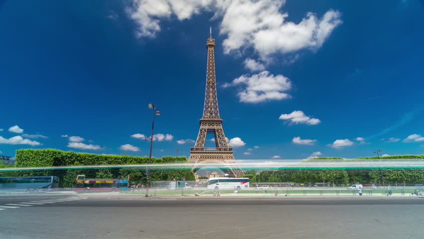 Eiffel Tower on Champs de Mars in Paris timelapse hyperlapse, France. Blue cloudy sky at summer day with green lawn and fountain with traffic around Royalty-Free Stock Footage #1103871687
