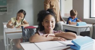 Animation of white bokeh light spots over smiling biracial girl at desk in diverse class. School, education, childhood and learning, digitally generated video.