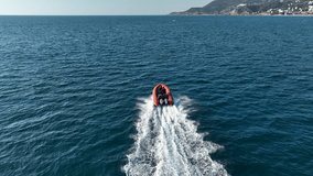 Aerial drone tracking video of red boat cruising in high speed in Mediterranean sea Police boat aerial view chasing on a sunny day checking documents high-quality background