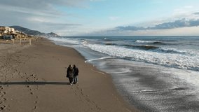 Middle-aged couple walking on a sandy beach by the sea or ocean. Man and woman on the shore in leisure time on a sunny winter day. - Powered by Shutterstock - Get 15% off with code: PIKWIZARD15