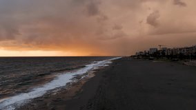 Road during sunset in Turkey Alanya, aerial cinematic view Orange sky and sun setting over calm waves of a gray sea or ocean. Tranquil, zen-like, cinematic scene. Slow motion video.