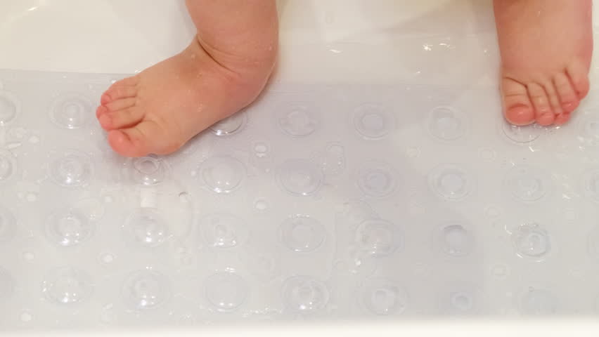 Baby legs is standing on a non-slip mat in the bathtub. Child boy foots washes on the anti slip carpet in the bathroom. Kid about two years old (one year ten months). Royalty-Free Stock Footage #1103879781