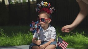 funny little kid in red, white, blue accessories sit green grass blow american colors windmill. national American flag is near child, his family celebrate 4 July Independence day, have picnic lawn - Powered by Shutterstock - Get 15% off with code: PIKWIZARD15