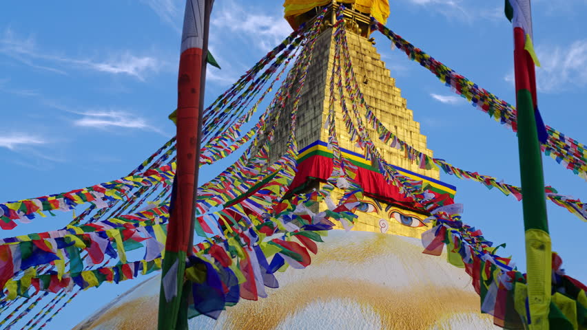 Lines of prayer flags blowing in the wind with the golden Boudhanath stupa temple in Kathmandu, Nepal