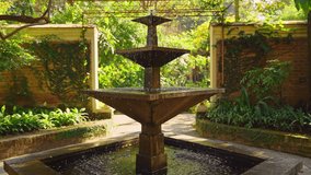 Moving towards an outdoor water fountain feature in slow motion with garden greenery and brick wall in the back  - Powered by Shutterstock - Get 15% off with code: PIKWIZARD15