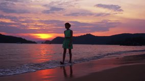 A video of a girl sand striding along the beach in Thailand during sunset