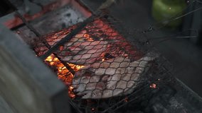 Grilling fresh fish on metal mesh clip and grilled using burning charcoal