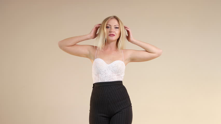Sexy blonde in an open top with thin straps and smiling at the camera and playing with her blond hair. Blonde gerl makes eyes. Isolated. 4K Resolution
