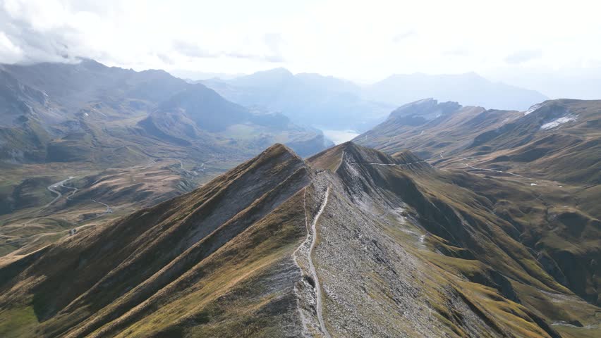 Aerial Epic Man standing on top of a mountain with panoramic view with mountains, lakes and clouds, Drone view, in the French Alps, France, Tour du Mont Blanc, near Refuge Croix du Bonhomme	
