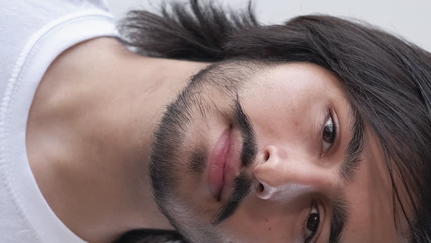 Vertical video. Male face. Fresh skin. Attractive brunette guy with mustache beard confident calm expression grooming appearance.