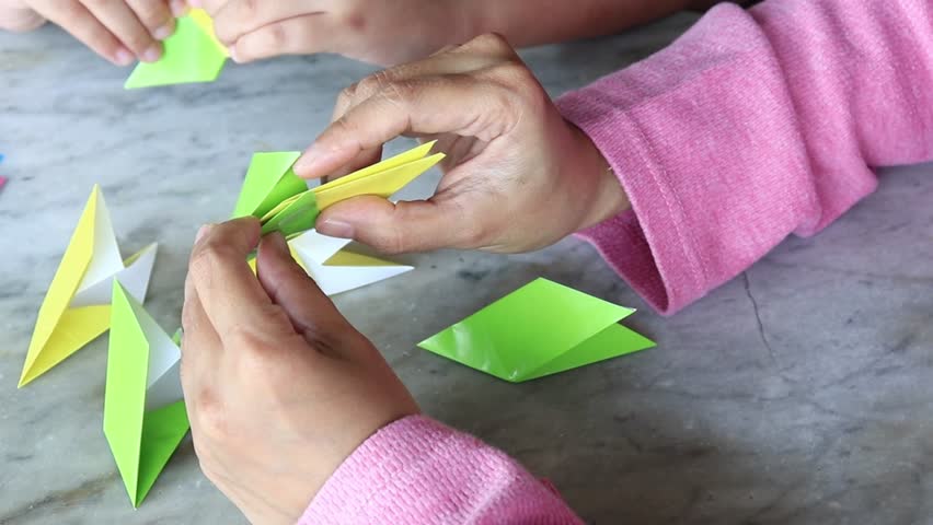 How to make DIY art and craft product. Folding multicolored origami paper tutorial. Fun education activity for kids at home. Isolated on textured background. 