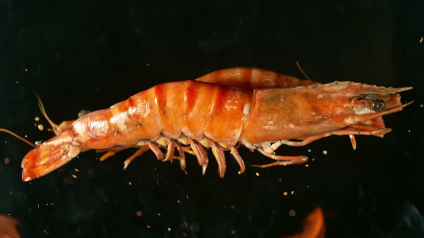 Super Slow Motion Shot of Falling Tiger Prawns on Cast Iron Grate with Fire Flames. Filmed on High Speed Cinematic Camera at 1000 FPS.