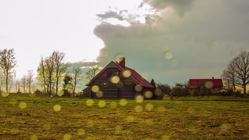 A view of a house in a rural area during the autumn season, with clouds and sunlight.
