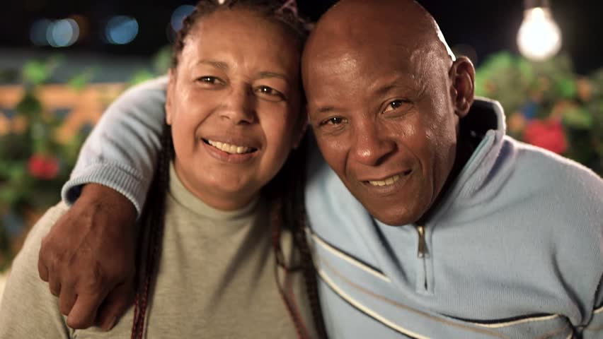 Happy african senior couple having fun smiling on camera and hugging together during night time at house terrace outdoor  Royalty-Free Stock Footage #1103913151