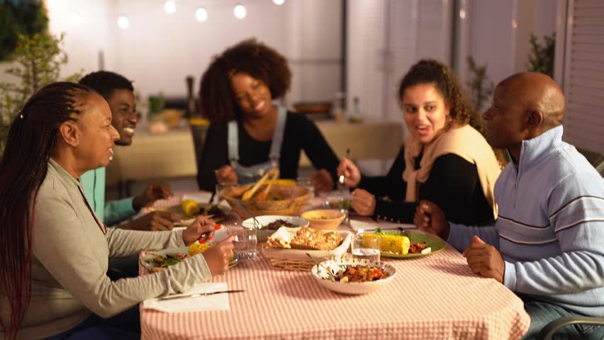Happy african family eating together healthy dinner at home terrace during summer time  Royalty-Free Stock Footage #1103913161