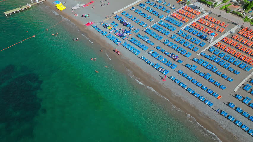 Positano Spiaggia - large Beach on the Amalfi Coast with chairs and umbrellas. Aerial drone view of Spiaggia Beach with town views and turquoise crystal clear transparent Mediterranean Sea in Italy.