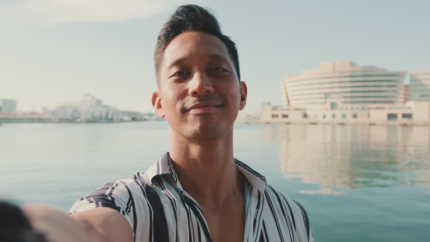 Close-up of young man standing on dock taking selfie with cell phone