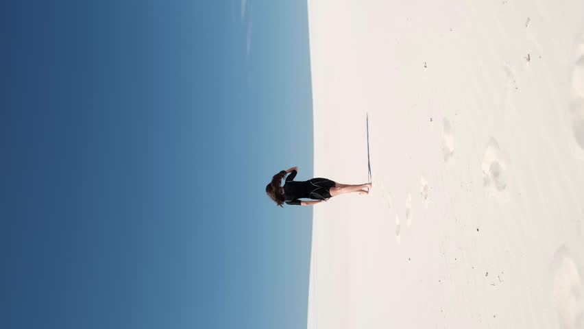 Fitness yoga woman stretching on the sand. Fit sportswoman doing yoga. Side view of the whole body of a slim young woman in a black top. Sport and healthy lifestyle concept
