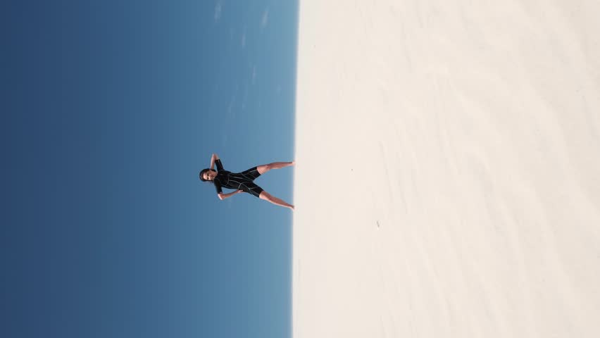 Fitness yoga woman stretching on the sand. Fit sportswoman doing yoga. Side view of the whole body of a slim young woman in a black top. Sport and healthy lifestyle concept
