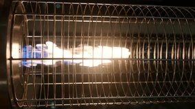 Vertical video of street gas heater in a outside patio of cafe or restaurant at night time. Burning open fire.