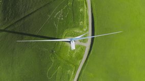 Top down aerial above white wind turbine rotating to generate eco friendly electricity. Renewable energy, sustainable development, environment friendly concept. Rotating drone shot, above view 4K USA