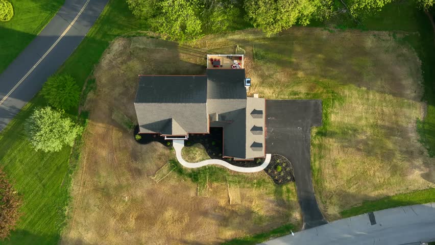 Top down aerial shot of large American home. New house with recently paved driveway and new grass. Completion of a construction project in the neighborhood.