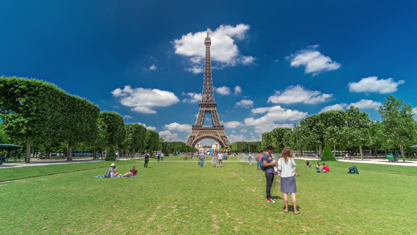 Eiffel Tower on Champs de Mars in Paris timelapse hyperlapse, France. Blue cloudy sky at summer day with green lawn and people walking around. Moving forward Royalty-Free Stock Footage #1103922127