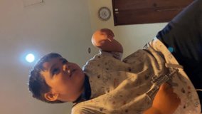 Vertical video 4 years old boy dance on the bed with lamp light at background