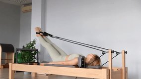 Woman training pilates on the reformer bed. Reformer pilates studio machine for fitness workouts in gym. Fit, healthy and strong authentical body. Fitness concept - Powered by Shutterstock - Get 15% off with code: PIKWIZARD15