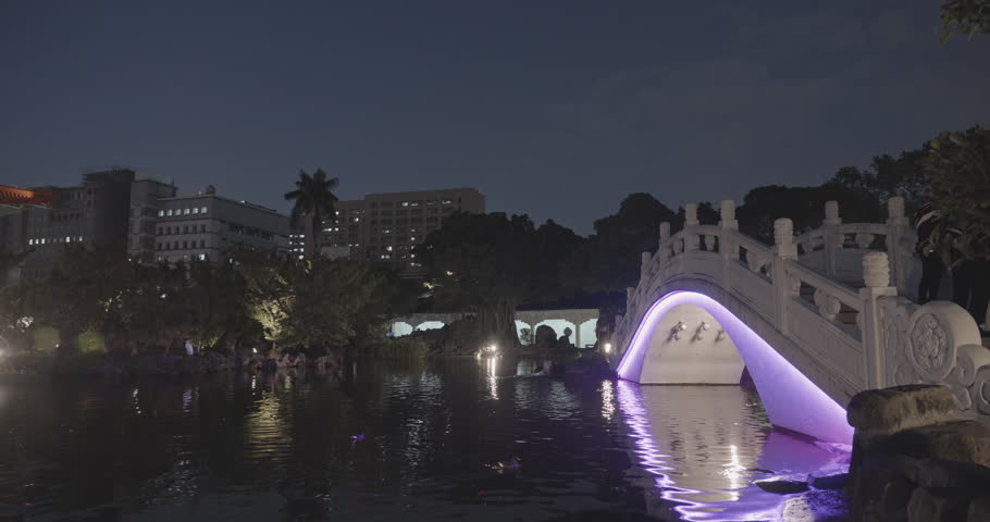 Panning left of Guanghua Ponds with bridge in Chiang Kai Shek (CKS) memorial park at night, Taipei, Taiwan