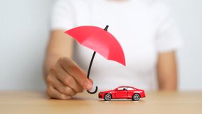 Businesswoman hand holding red umbrella and cover red car toy on table. Car insurance, warranty, repair, Financial, banking and money concept - Powered by Shutterstock - Get 15% off with code: PIKWIZARD15