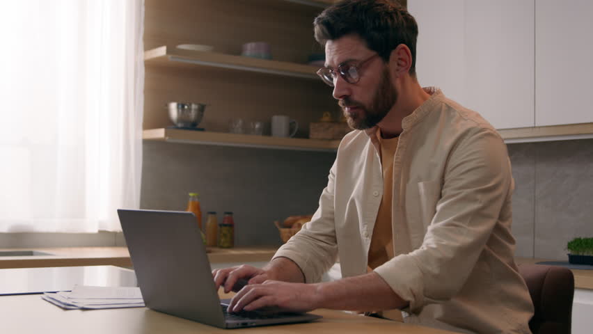 Caucasian busy freelancer man working distant from home work with laptop at kitchen exhausted businessman take off glasses suffering from eye strain pain job break from computer dry eyes overworking Royalty-Free Stock Footage #1103945833