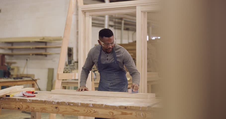 Carpentry, creative and a black man sanding a plank in his factory for professional woodwork. Safety goggles, manual labor and expertise with a happy male carpenter working in his design workshop Royalty-Free Stock Footage #1103946157