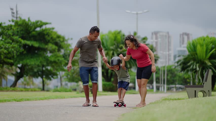 happy family in the park playing with son riding skateboard. Mom dad and son walk holding hands in the park. Parents and fun with children 
 Royalty-Free Stock Footage #1103952981