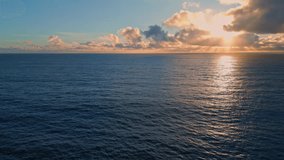 Rippling ocean surface reflecting beautiful sunset. Aerial view breathtaking marine sunrise with bright golden rays shining on dark sea water slow motion. Sundown sunlight breaking through clouds. - Powered by Shutterstock - Get 15% off with code: PIKWIZARD15