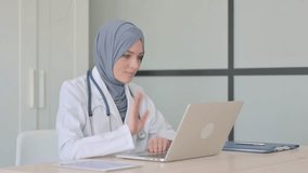 Online Video Chat by Muslim Female Doctor on Laptop in Clinic