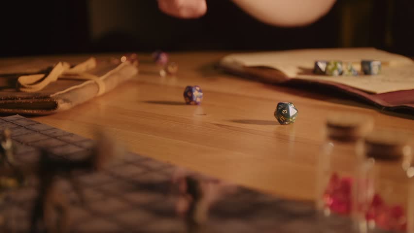 A man rolls dice for a fantasy roleplaying game with a map and miniatures in the foreground Royalty-Free Stock Footage #1103957749