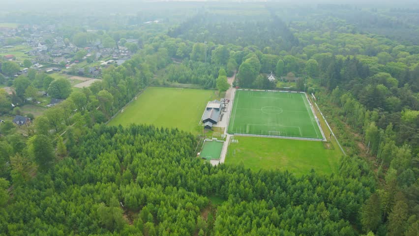 Aerial orbit of beautiful soccer fields surrounded by a green forest in summer Royalty-Free Stock Footage #1103962401
