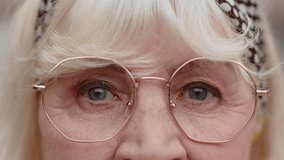 Extreme close-up macro portrait of wrinkled face in glasses. Old senior beautiful woman's eyes, looking at camera. Gray eyes of grandmother, elderly lady female. Mature granny opening blinking eyes - Powered by Shutterstock - Get 15% off with code: PIKWIZARD15