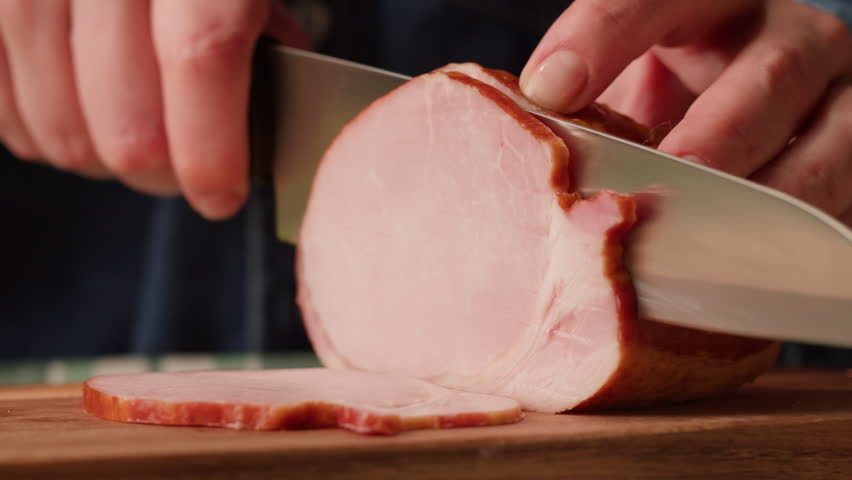 Woman slices ham bacon meat thick pieces on a wooden board, beef or pork jamon. Chef cooking breakfast, smoked bacon in cafe. 